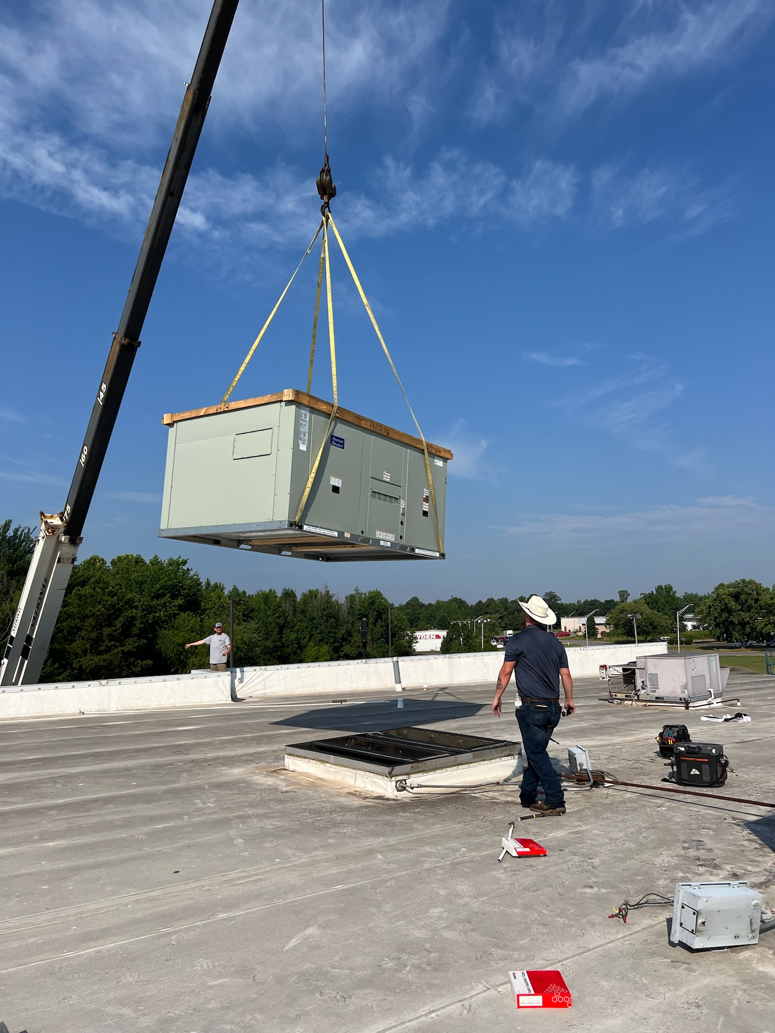 An HVAC unit being lowered with a crane.