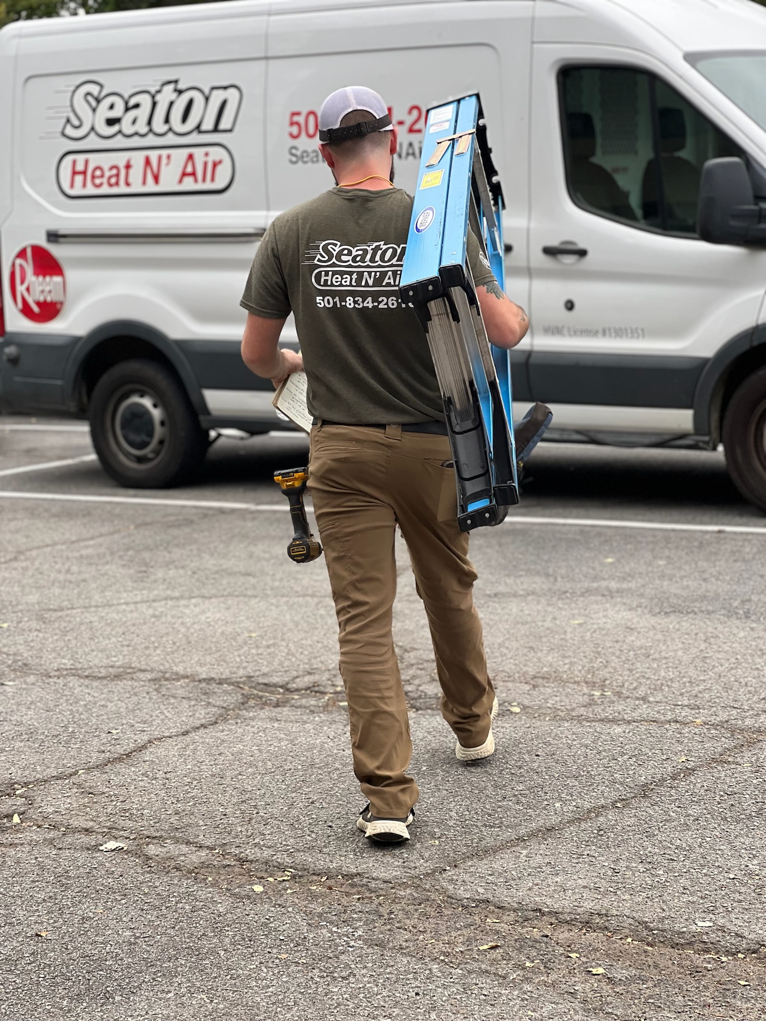 Man carrying a ladder to a branded Seaton Heat N' Air & Electric van.
